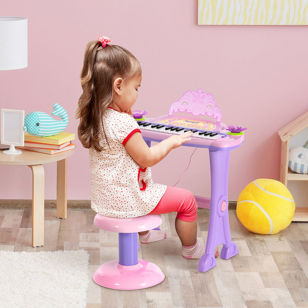 Child playing with pink 32-key kids electronic keyboard piano with microphone
