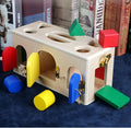 Wooden Montessori shape lock box with colorful wooden shapes scattered around showing locking doors and shape holes on top