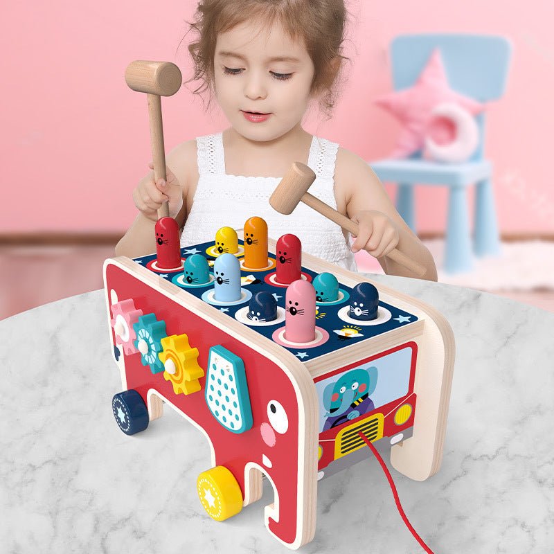 Toddler girl hammering pegs on Montessori elephant pounding bench toy with two wooden mallets