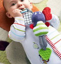 Baby chewing on green teether of soft plush musical elephant hanging toy