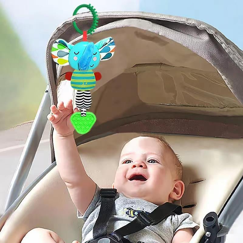 Musical elephant teether toy hanging from stroller canopy while baby reaches up smiling