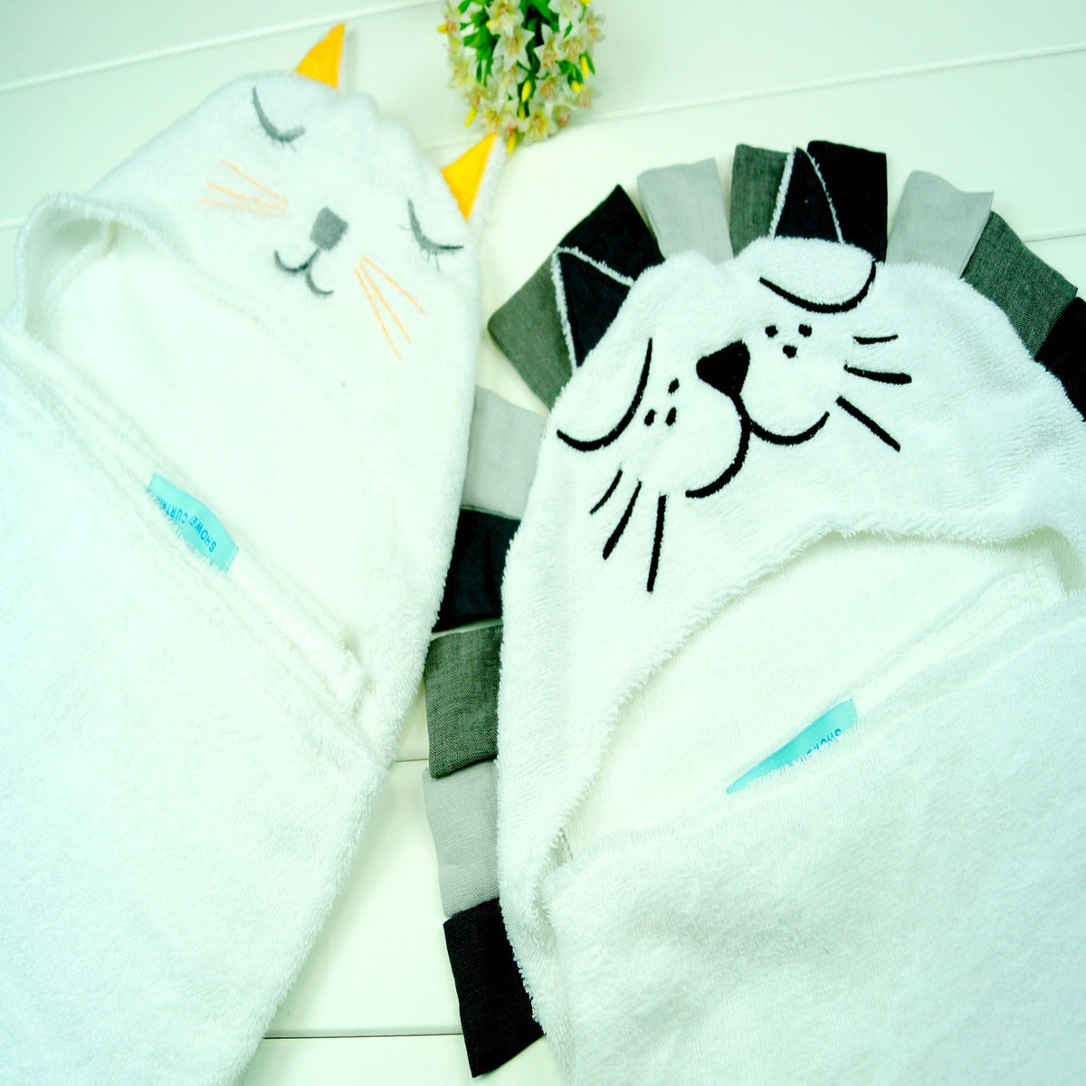 Both cat and lion hooded baby bath towel styles laid flat showing embroidered hoods side by side