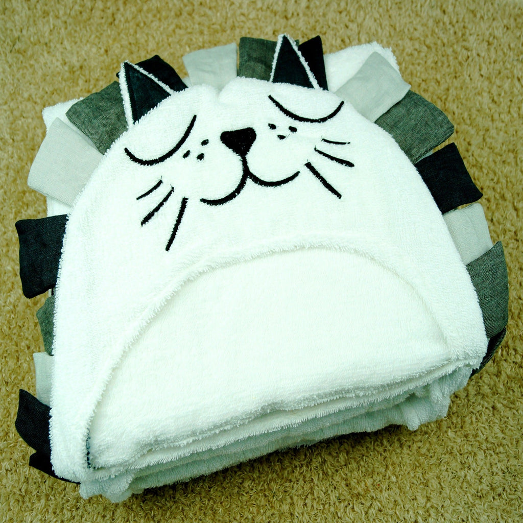 Folded lion hooded baby bath towel with embroidered face and dark mane ears on carpet