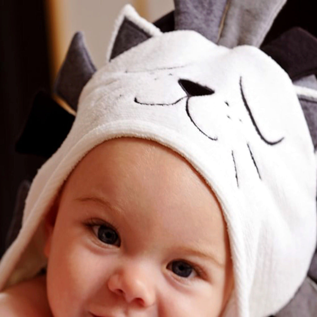 Close-up of baby wearing lion hooded bath towel showing embroidered face and dark mane hood detail